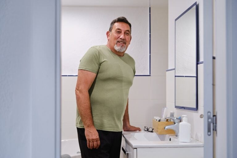 man wearing green standing in front of bathroom mirror